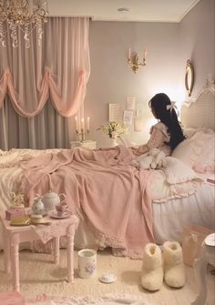 a woman sitting on top of a bed next to a table with cups and saucers