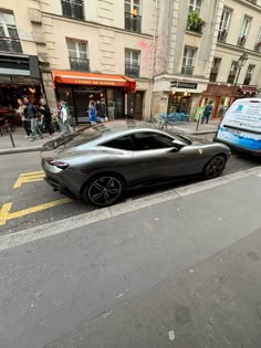 a black sports car is parked on the side of the road next to a bus