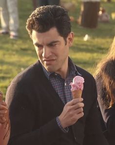 a man holding an ice cream cone in his hand while standing next to other people