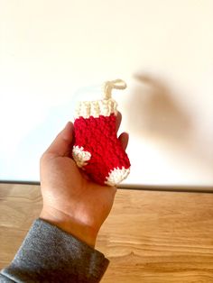 a hand holding a crocheted red and white object