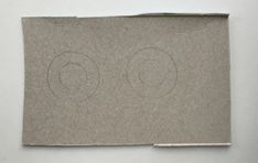 a piece of brown paper with two circles drawn on the bottom and one circle in the middle