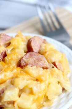 a white plate topped with ham and cheese casserole next to a knife and fork