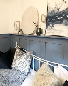 a bed with blue and white pillows on top of it next to two framed pictures