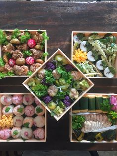 four wooden boxes filled with different types of sushi and other foods on top of a table