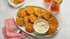 some fried food is on a plate with a bowl of dip and two glasses of tea