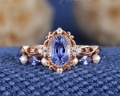 a close up view of a ring with an oval blue stone surrounded by white pearls