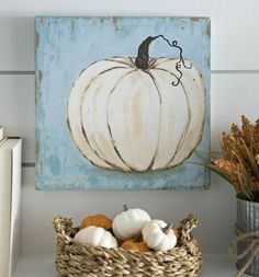 a white pumpkin sitting on top of a shelf next to a basket filled with oranges