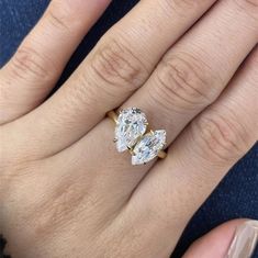 a woman's engagement ring with two pear shaped diamonds