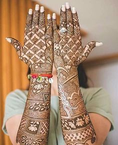 a woman's hands with henna tattoos on them