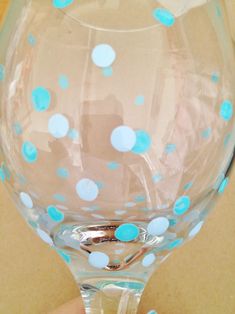 a hand holding a wine glass with blue dots on it