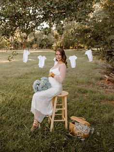 a pregnant woman sitting on a stool in the grass