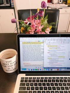 an open laptop computer sitting on top of a table next to a cup of coffee