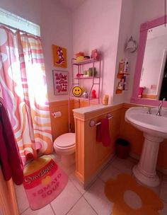 a bathroom with pink and orange decor on the shower curtain, toilet seat cover, sink and mirror