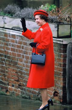 a woman in a red coat and hat waves