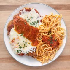 a white plate topped with pasta and meatballs covered in sauce on top of a wooden table