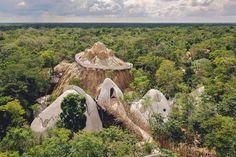 an aerial view of trees and rock formations in the middle of a forest with clouds overhead