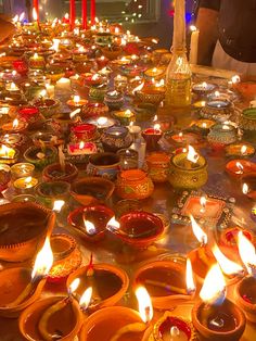 many candles are lit in bowls on the table