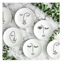 six plates with faces drawn on them