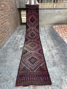 an old rug laying on the ground in front of a brick wall