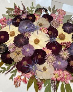 a bunch of flowers that are sitting on a white tablecloth with purple and pink flowers in the center