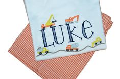 This is  such a cute construction truck shirt with the child's name being constructed by various construction vehicles sitting on a dirt road.  Placement of the vehicles may vary based upon the name.  You will be able to choose short sleeve (SS)  or long sleeves (LS).  The inside of the shirt has a soft covering over the back of the embroidery.  There is also an option to add orange gingham shorts or pants with the shirt.  If selected the bottoms are fully lined with an elastic waist. Construction Shirt, Orange Gingham, Truck Shirt, Truck Shirts, Baby Boy Clothing Sets, Gingham Shorts, Dirt Road, Spring Hill, Construction Vehicles