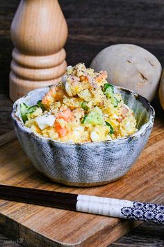 a bowl filled with food sitting on top of a wooden cutting board