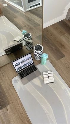 an open laptop computer sitting on top of a wooden floor next to a mirror and other items