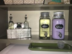 three jars with labels on them are sitting on a shelf next to a green tray