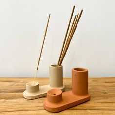 two ceramic vases with sticks sticking out of them on a wooden table next to each other