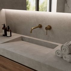 a bathroom sink with two gold faucets and soap bottles on the counter top