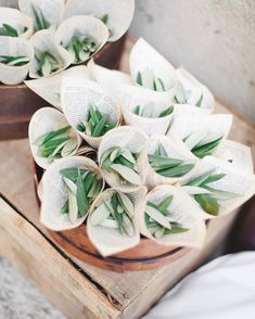 two wooden bowls filled with white flowers on top of a wood table next to an open book