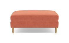 an orange ottoman with wooden legs