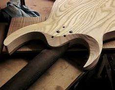 a wooden guitar being worked on by a man in the process of making it out of plywood