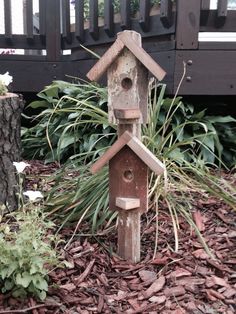 a wooden birdhouse sitting on top of a pile of leaves