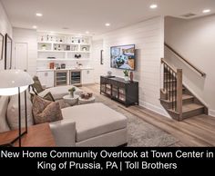 a living room filled with furniture and a flat screen tv mounted to the wall next to a stair case