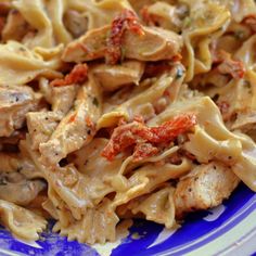 a blue and white plate topped with pasta covered in sauce