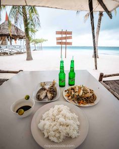 there is a plate of food and two bottles on the table at the beach side