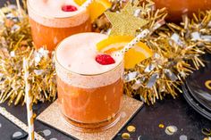 two glasses filled with drinks sitting on top of a table next to confetti