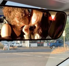 a man and woman kissing in the rear view mirror