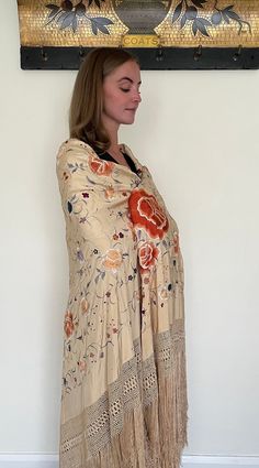 Here is a beautiful antique silk embroidered Manton de Manila shawl dating to the early part of the 20th century circa 1900 to 1910. The silk ground is in a rare buttermilk colour, I think that the listing photos which shows it worn by our model give a good indication of the actual colour. The richly coloured embroidery is in colours including orange, blue, lilac and white and it has long fringing and a hand knotted deep border to each side. The design includes large peony flowers and smaller fl Vintage Cream Silk Scarf, Embroidered Silk Shawl Scarf, Silk Shawl Scarf, Embroidered Silk Shawl, Traditional Beige Silk Scarves, Vintage Pashmina Shawl For Wedding, Beige Silk Shawl Scarf, Beige Shawl Dupatta, Traditional Cream Dupatta With Floral Print