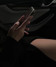 a woman is using her cell phone while sitting in the backseat of a car at night