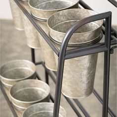 several metal buckets are stacked on a rack