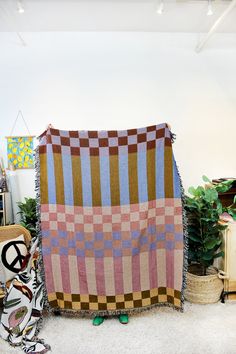 a blanket sitting on top of a white floor next to a chair and potted plant