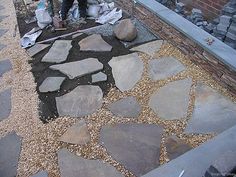 a man standing next to a pile of rocks on top of a gravel covered ground