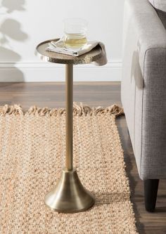 a small table with a glass on it in the middle of a room next to a couch