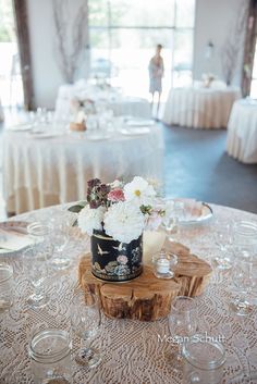 a table topped with a vase filled with white and pink flowers on top of a wooden slice