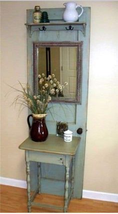 a small table with a vase and mirror on it