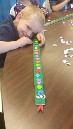 a young boy sitting at a table with a paper decoration on it