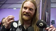 a man with long hair holding microphones in front of him and talking to the camera