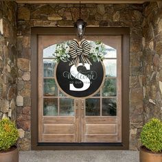 the front door to a stone building with two planters and a sign that says welcome